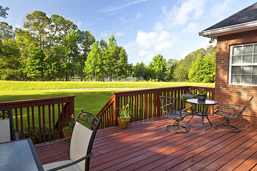 Redone and refurnished backyard wooden deck with crisp green lawn in the background