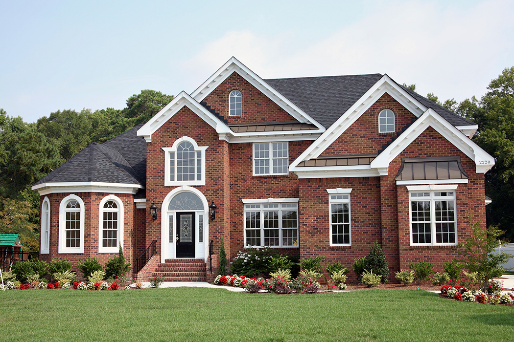 Elegant red brick house with gray roof and well maintained lawn