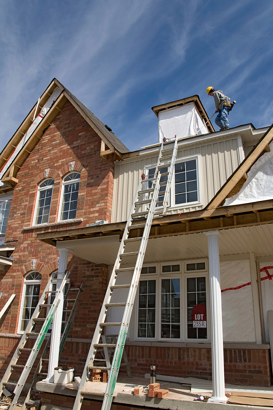 Workers on a roof redoing the siding and roof shingles